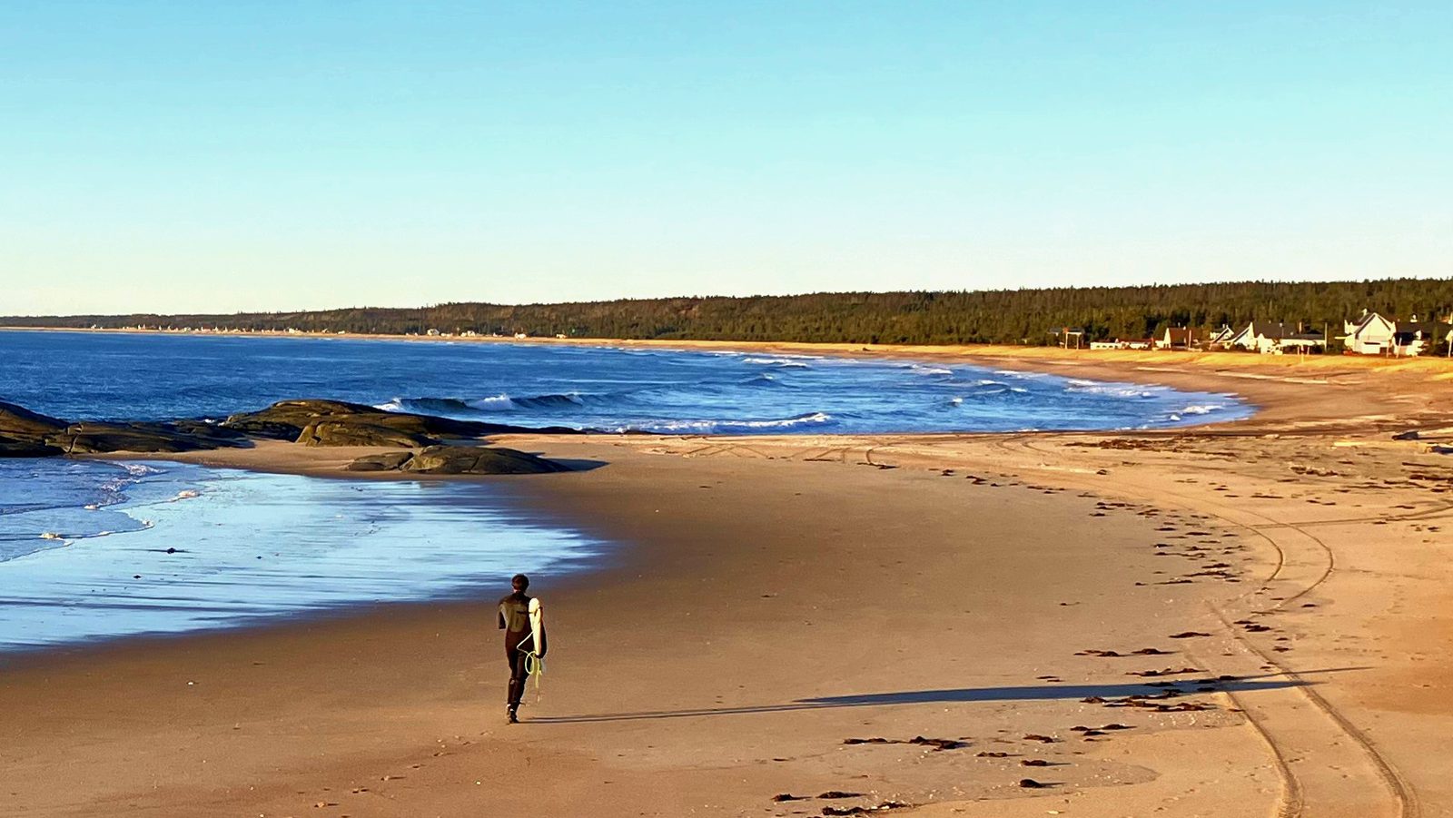 Walking on a beach in Sept-Îles with a surfboard